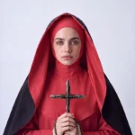 Portrait of a woman dressed in red religious attire holding a symbolic cross, exploring the fragile boundary between faith, conviction and war through contemporary fine art.